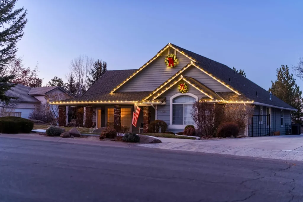 Craftsman-style house decorated with Christmas lights along the roofline and porch
