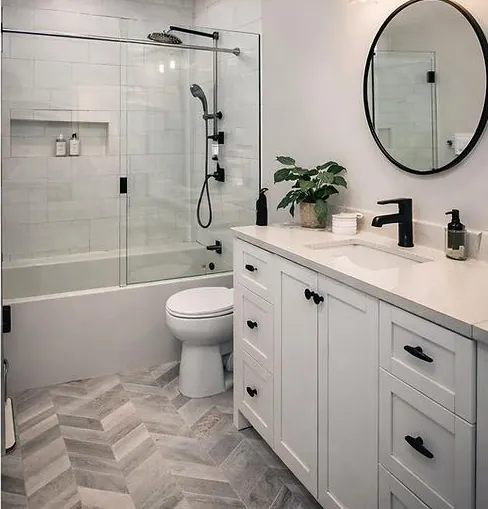 Finished bathroom remodel with glass shower, white vanity and herringbone tile floor